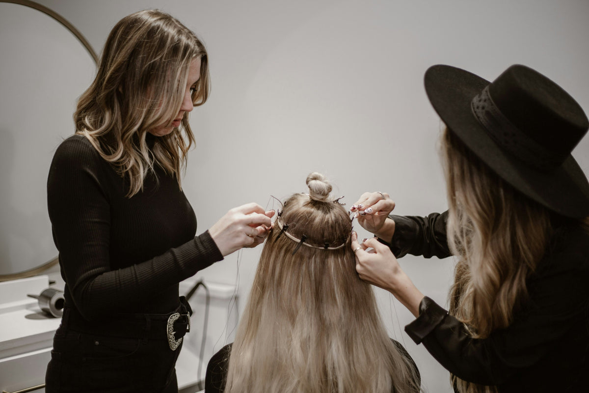Kapper plaatst extensions bij een klant in de salon